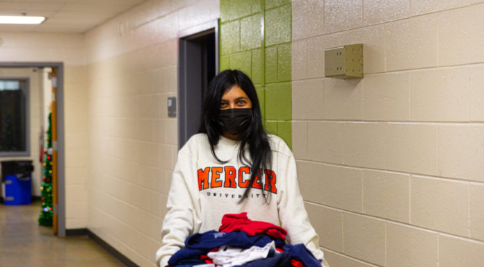 How to get involved in community service at Mercer | Ask Kelly A young woman wearing a Mercer shirt carries a bin of clothes