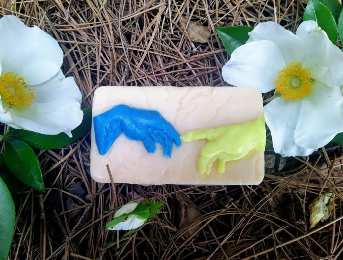 a bar of soap featuring a blue hand reaching out to a yellow hand