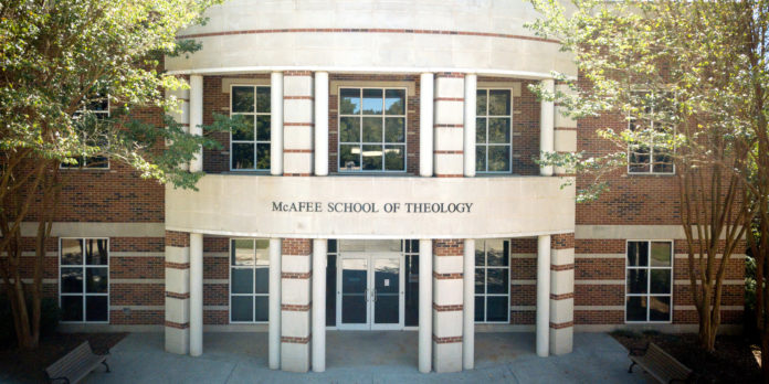 Front entrance of McAfee School of Theology with brick facade, glass doors, and surrounding trees.