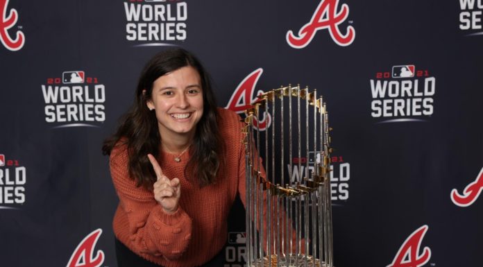 Business alumna helps make Braves games special for fans A smiling woman stands next to the world series trophy.