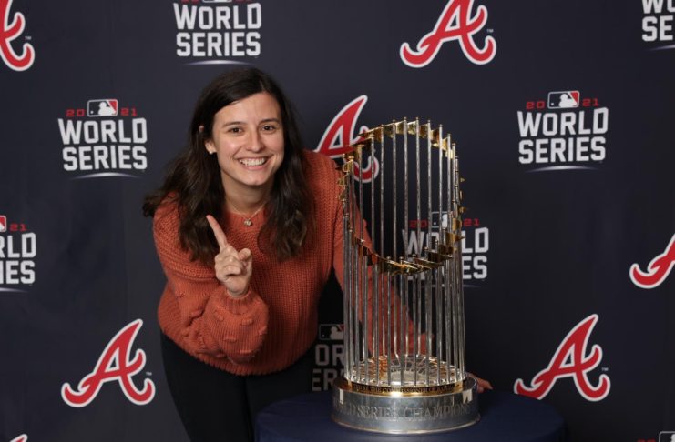 A smiling woman stands next to the world series trophy.