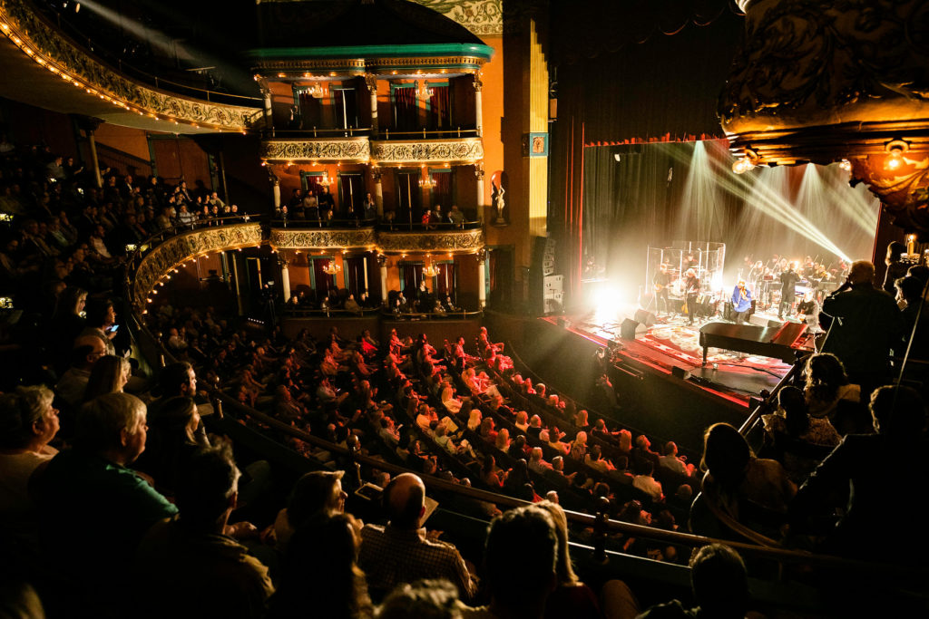 A stage of performers is photographed from the balcony