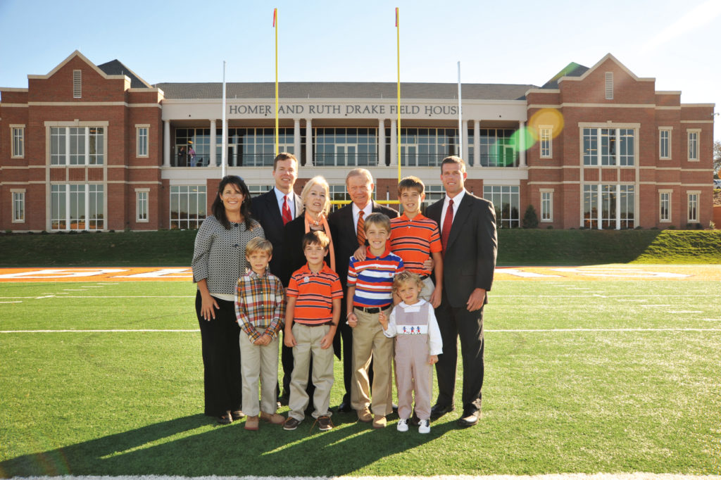 A family stands in front of the Homer and Ruth Drake Field House.