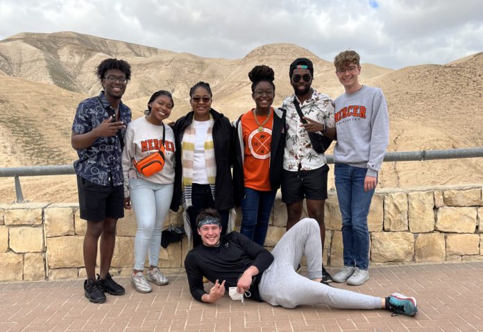 A group of six students and their professor pose for a photo in the desert.