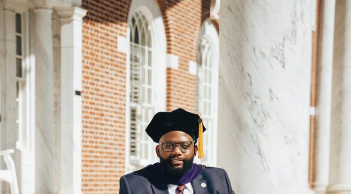 Graduate Spotlight: J. Chad Capers A young man wearing a suit sits on steps with law books next to him