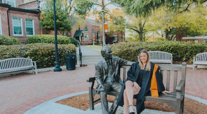 Graduate Spotlight: Jordan Leet A woman wearing a graduation gown sits next to a statue of Jesse Mercer