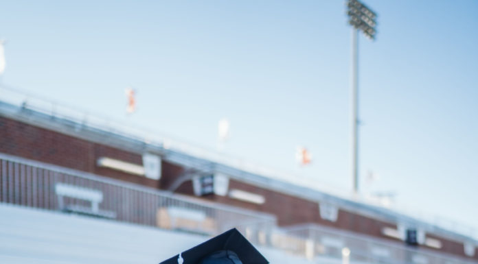 Graduate Spotlight: Mia Spinola A woman sits on bleachers wearing a cap and gown