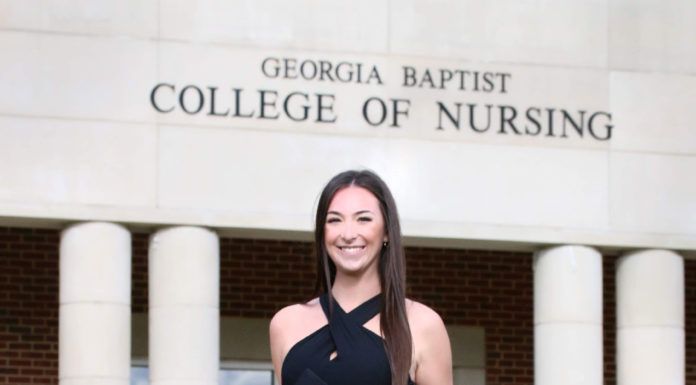 Graduate Spotlight: Molly McCreath A young woman holding a graduation cap stands in front of a building that says Georgia Baptist College of Nursing