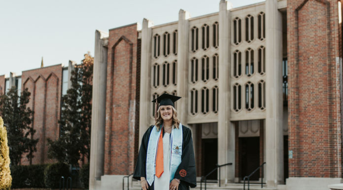 Graduate Spotlight: Morgan Miller A young woman wearing a graduation gown stands in front of a building