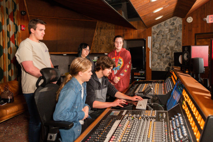 Students sit at a sound board