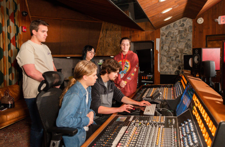 Students sit at a sound board