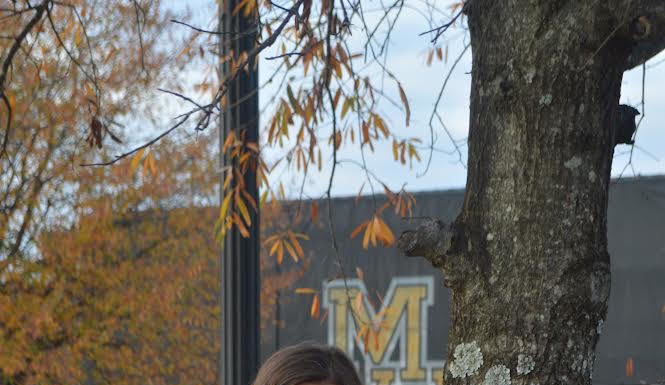 Graduate Spotlight: Patricia Presley A young woman wearing an orange Mercer T-shirt leans against a tree