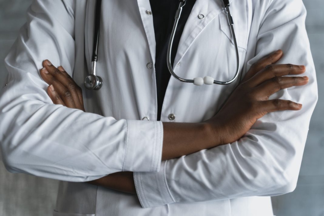 black woman in doctor's coat crosses her arms