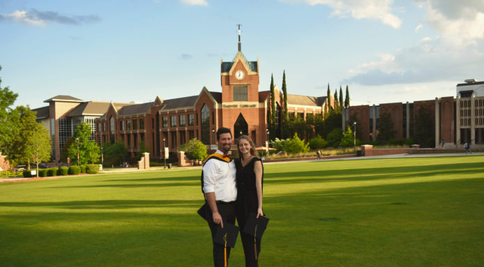 Graduate Spotlight: Earl and Logan Ford A man and woman stand in a grassy field in front of a clock tower