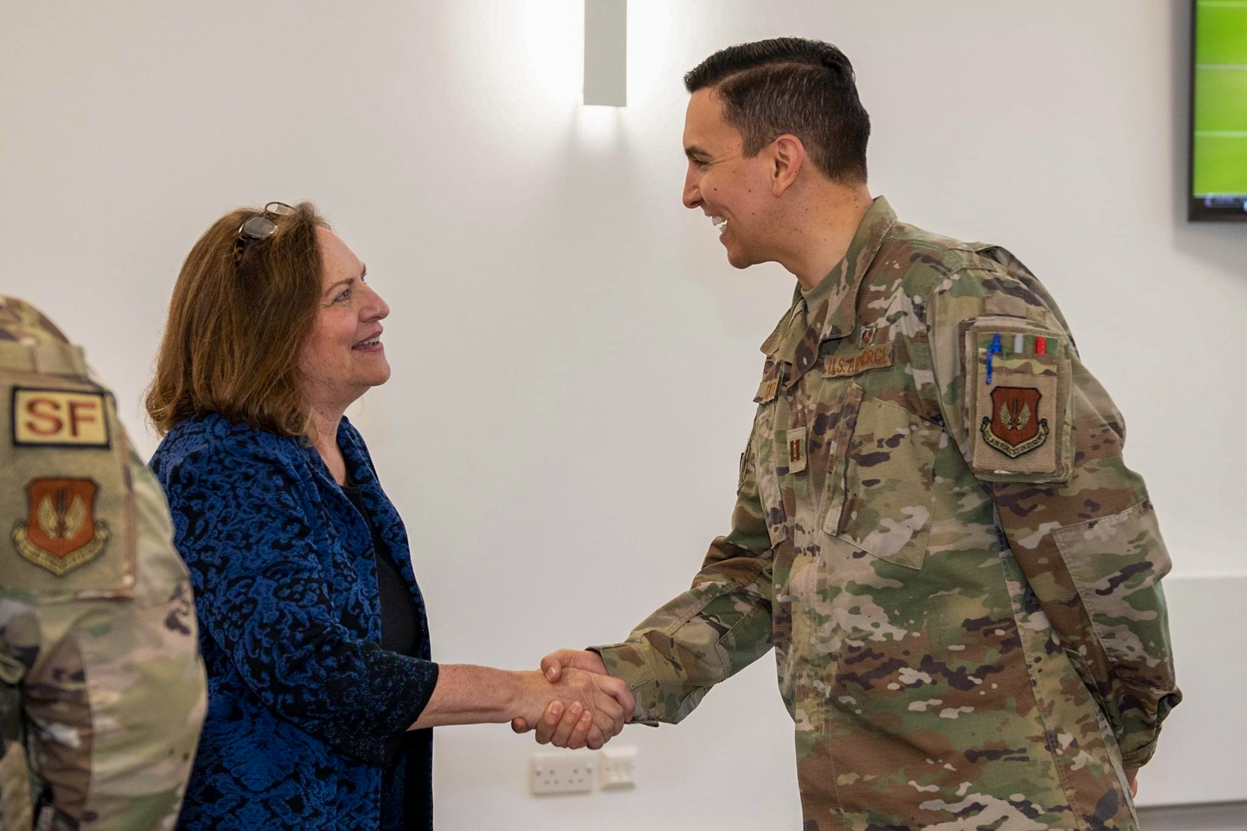 a man wearing military fatigues shakes a woman's hand