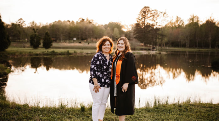 Daughter graduates from College of Nursing 12 years after her mom Two women stand side by side in front of a lake. The younger woman on the right wears a graduation gown.