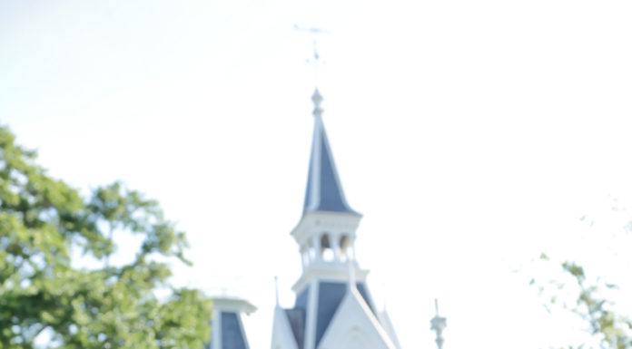 Graduate Spotlight: Michelle Ferlita A young woman wearing a white dress and an orange stole stands in front of building.