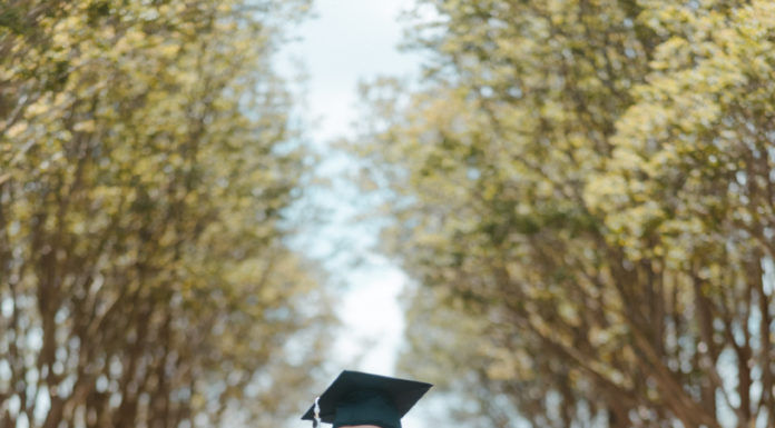 Graduate Spotlight: Sierra Hathaway A young woman wearing a graduation cap and gown stands outside in front of steps