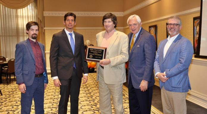 German professor awarded inaugural Mike MacCarthy Mentorship Award A man holding an award plaque is flanked by four men. The plaque reads: Mike MacCarthy Mentorship Award Presented to Edward Weintraut April 12, 2022