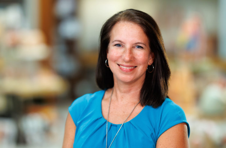 Dr. Christy Chancy Bridges smiles at the camera in an indoor setting with a blurred background.