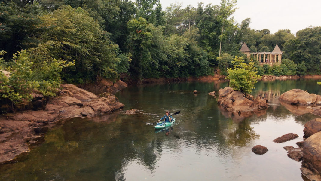 a man kayaks down the middle of a river