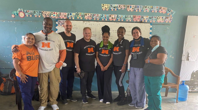 Mercer On Mission team helps children, communities coping with trauma in Honduras eight people smile during a group photo. the six people in the middle wear a shirt that says mercer on mission honduras 2022