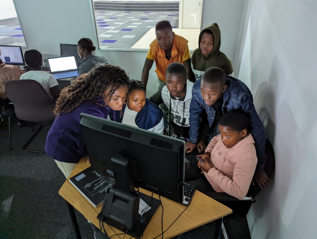 A Mercer students helps Cape Town children with a computer science lesson.