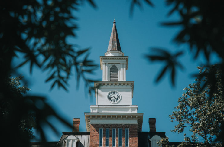 A white clock tower with a steeple atop Willingham Hall.