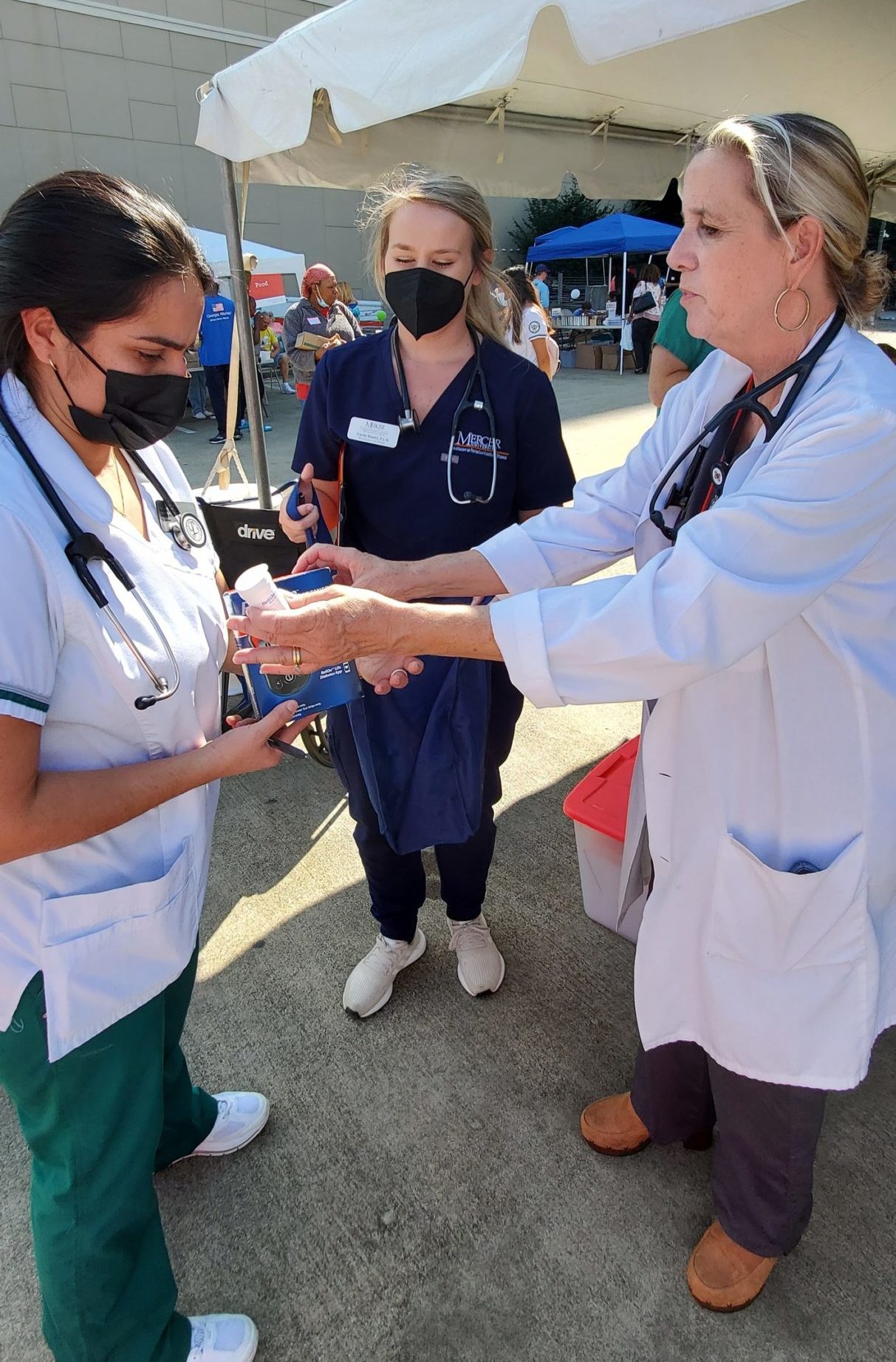 Erin Lepp, at right, clinical associate professor and coordinator of physician assistant community engagement and medical team lead for the event, gives diabetic supplies to students volunteering at the event.