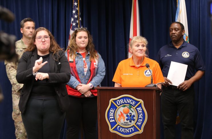 Mercer student Samantha Cannon (in red vest) is shown at a press briefing in Orange County, Florida, following Hurricane Ian. Speaking is Lauraleigh Avery, Division Chief of Orange County Fire Rescue. Shown at left is a National Guard member and an interpreter and at right is Orange County Mayor Jerry Demings.