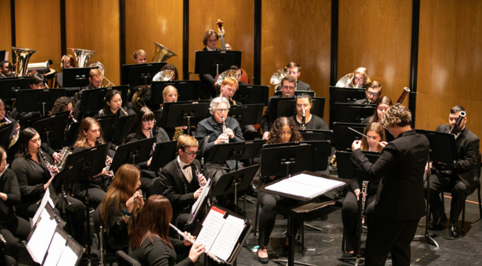 Mercer Wind Ensemble and Rutland High band combine for joint concert wind musicians wearing black perform on stage