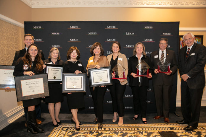 people stand holding awards in front of a mercer backdrop