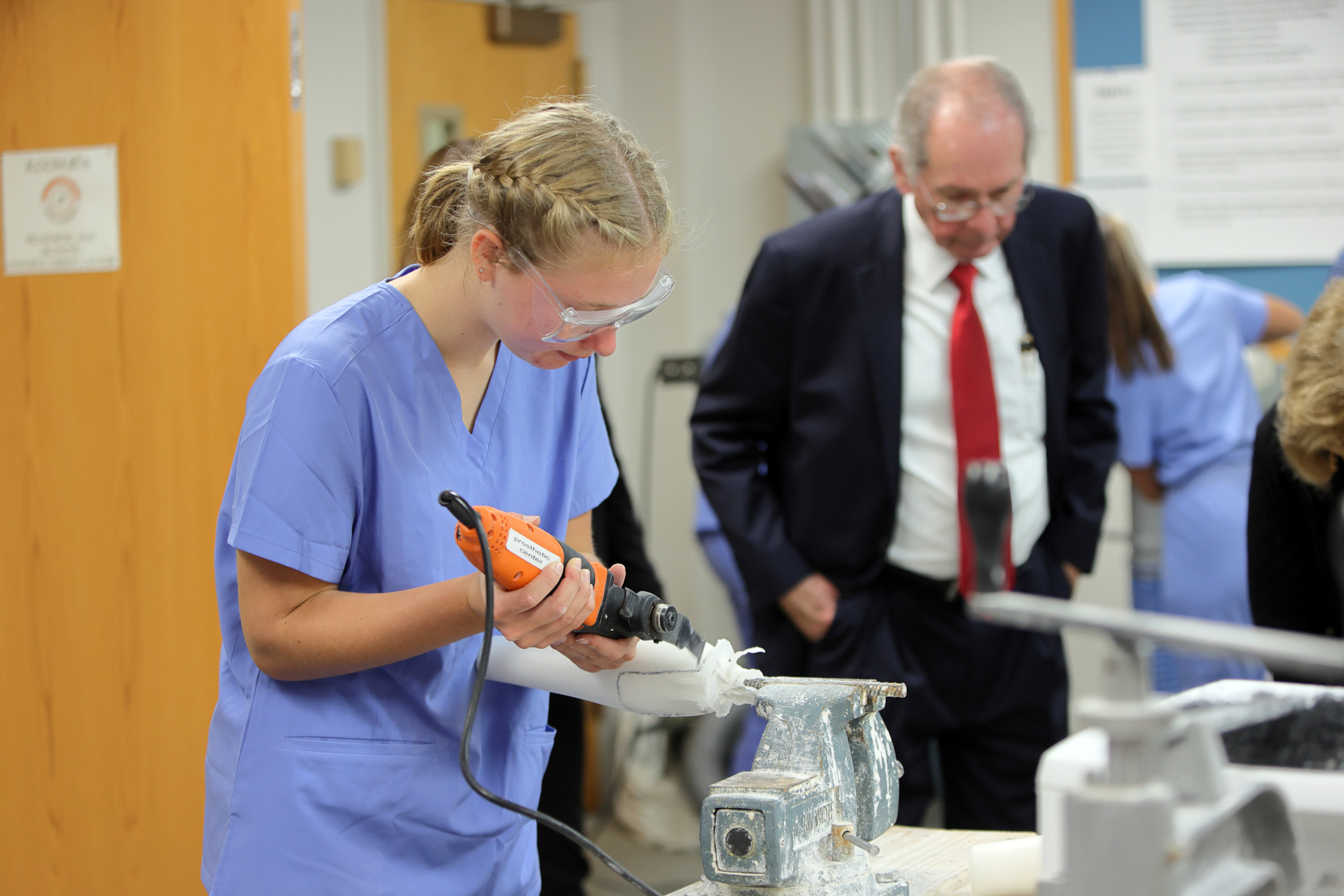 A woman in scrubs uses a tool on a prosthetic limb