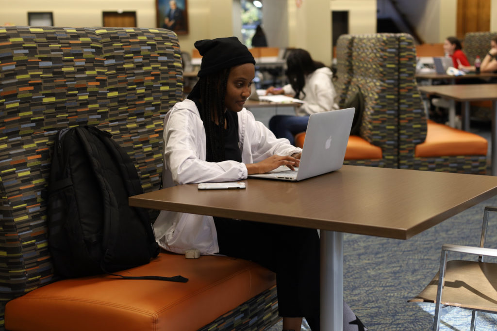 A student sits in a booth looking at a laptop