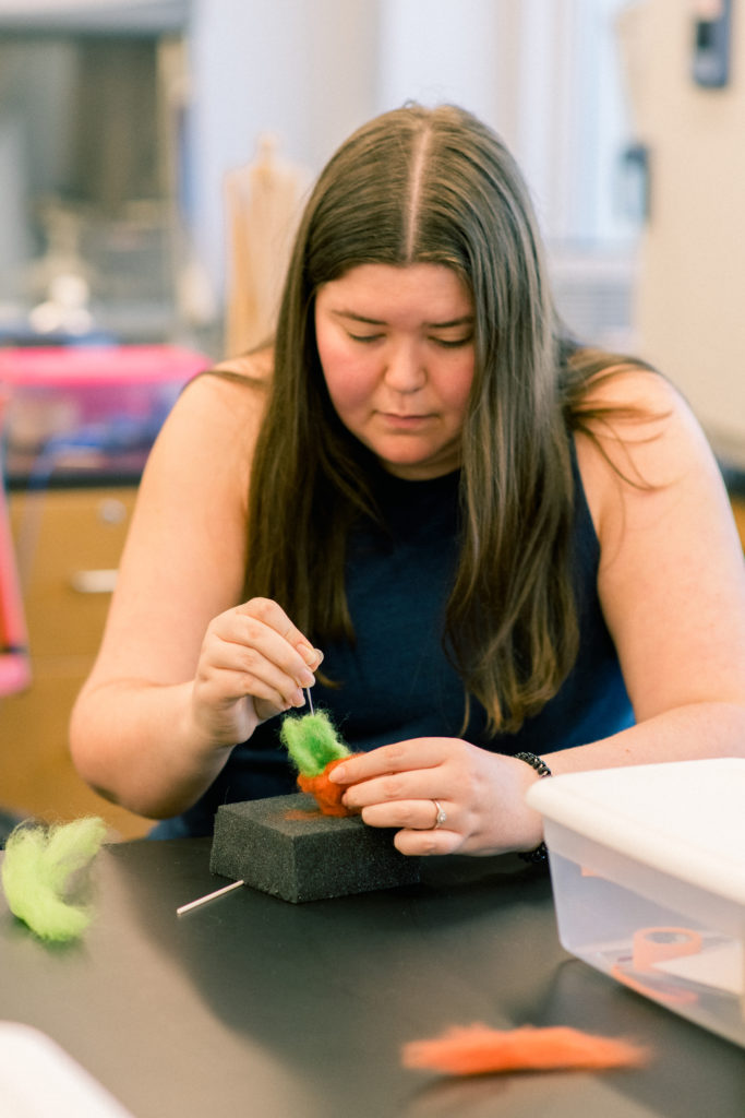 A female student works on a needle felt animal.