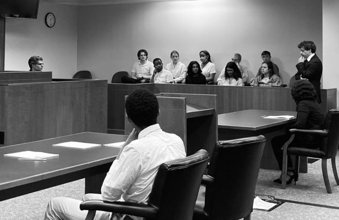 a black and white photo shows people sitting in a jury box in a courtroom.