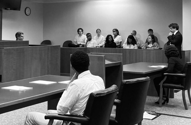 a black and white photo shows people sitting in a jury box in a courtroom.