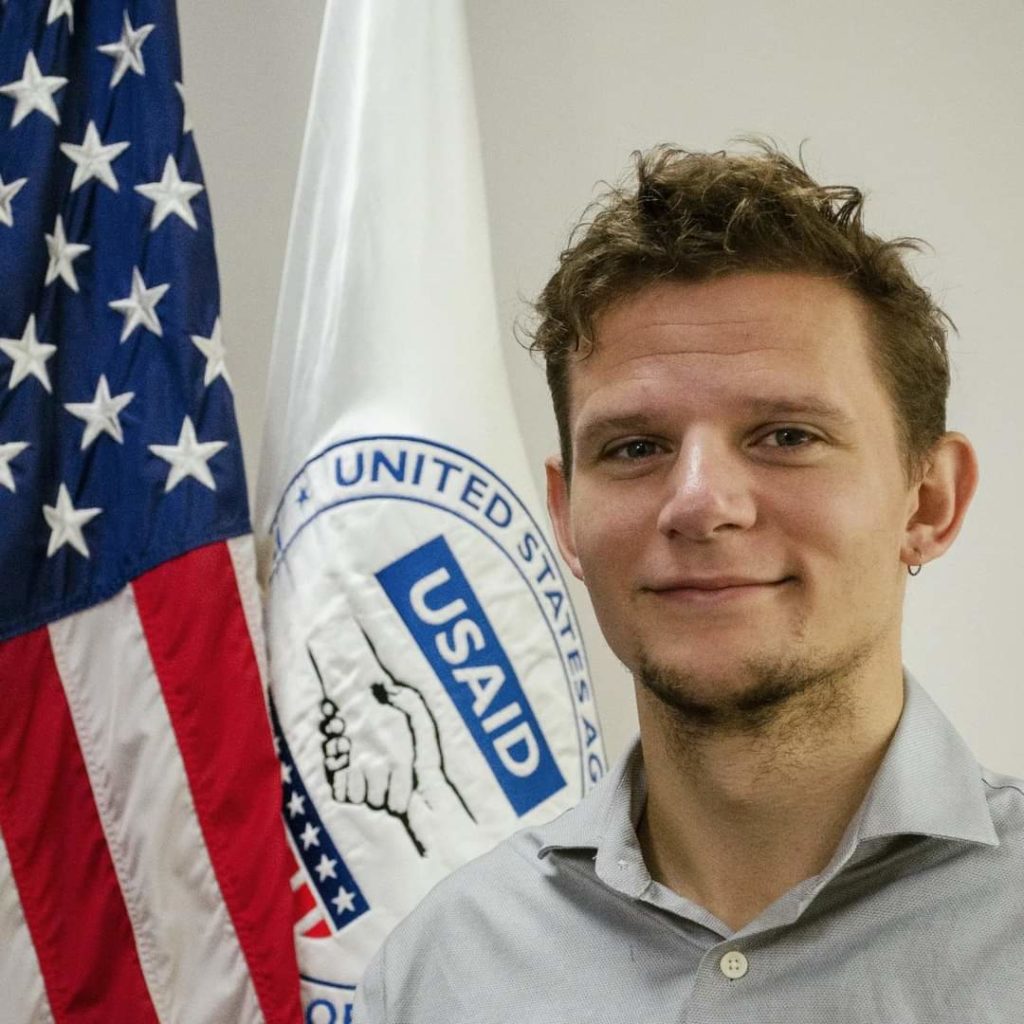 Aaron Scherf with the USAID flag in Colombia.