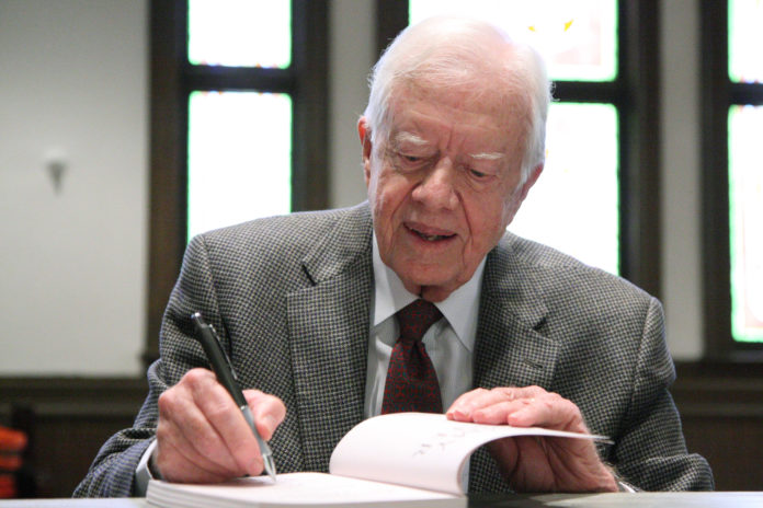 Jimmy Carter signs a book.