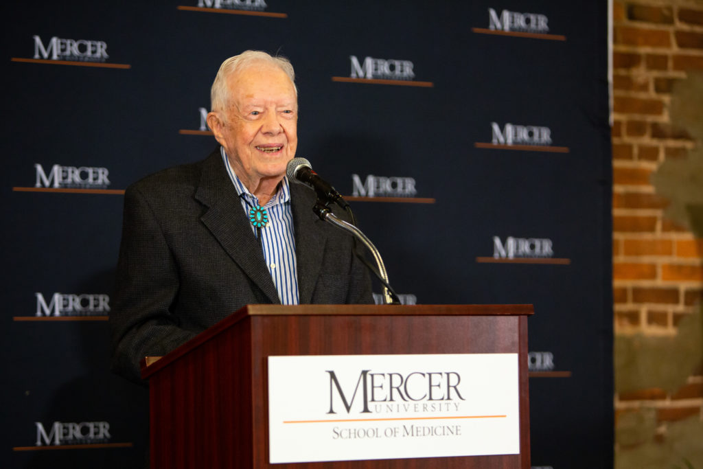 Jimmy Carter speaks at a podium in front of a Mercer backdrop.