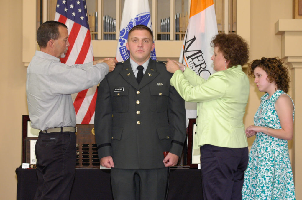 aj pitchford is pinned with his new rank by his dad on his left and mom and younger sister on the right. 