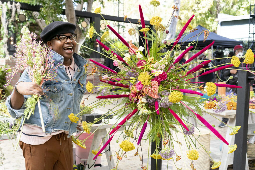 Canaan Marshall stands beside a vibrant floral arrangement.