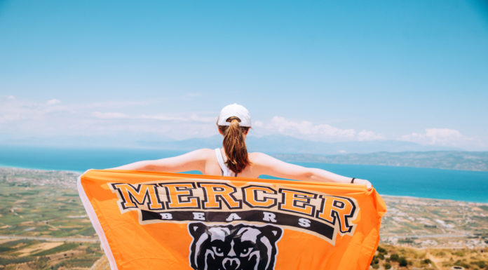 Mercer University prioritizes international education experiences for all a student holds out a mercer flag overlooking greece