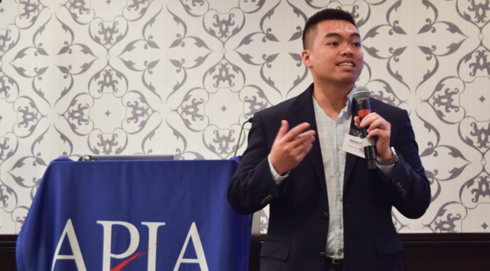 Mercer alumnus’ experience with immigration system inspires advocacy for change raymond partolan speaks into a microphone next to a banner that says APIAVote