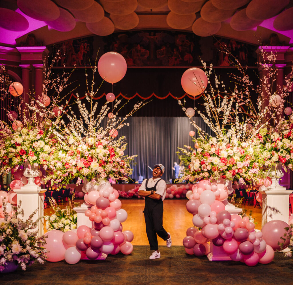 Canaan Marshall stands in a banquet room, surrounded by pink balloons and flower arrangements.