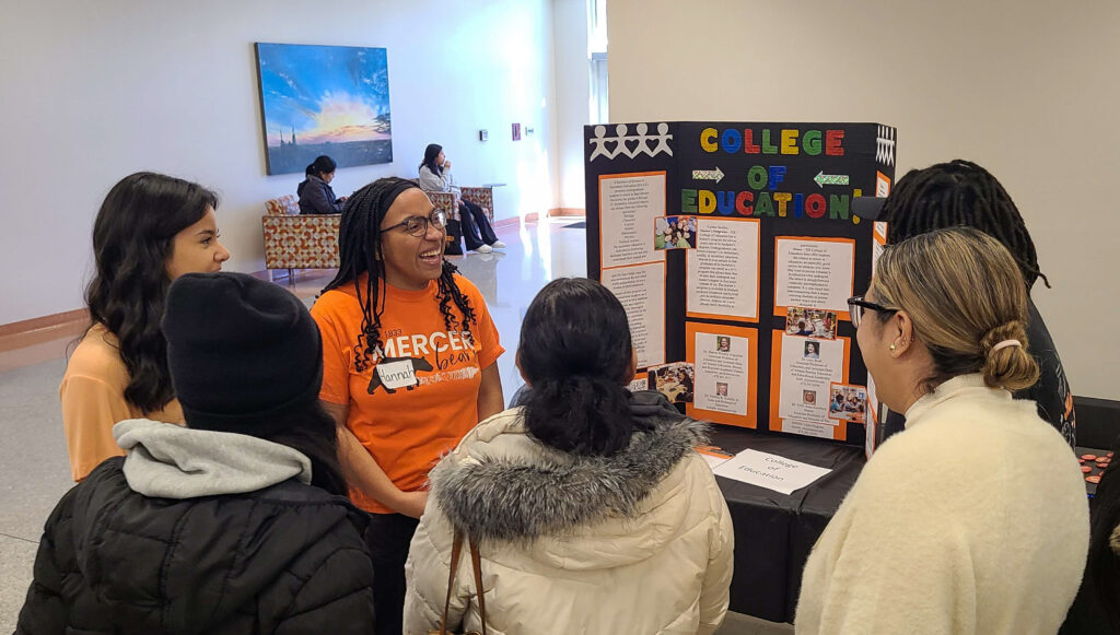 Mercer students talk with people beside their poster.