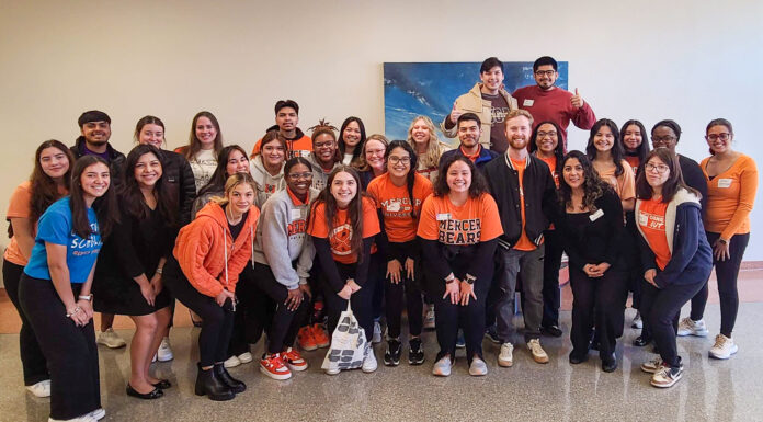 Students translate admissions materials to Spanish to help reach Hispanic community Mercer students and faculty huddle for a group photo, many of them in Mercer apparel.