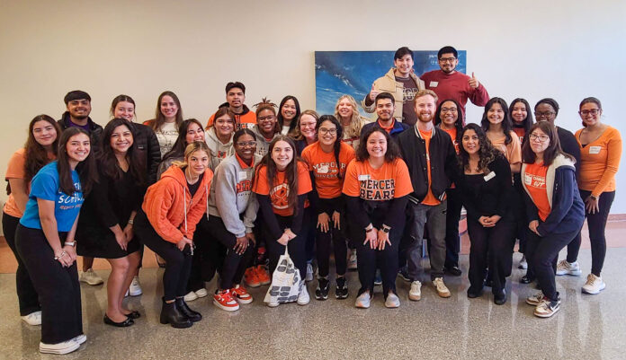 Mercer students and faculty huddle for a group photo, many of them in Mercer apparel.