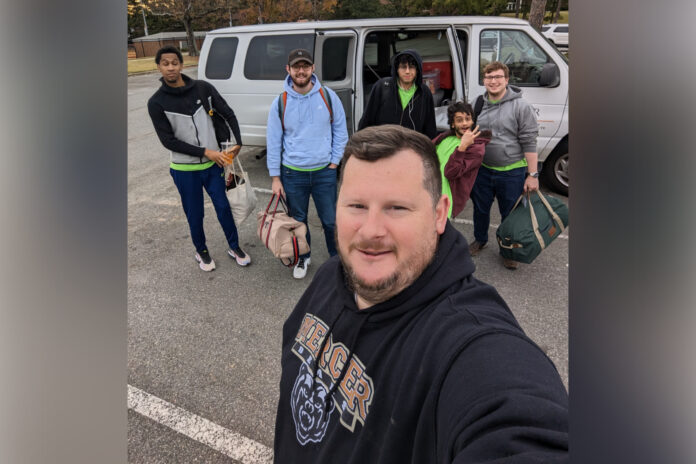 A selfie of five people in front of a van.
