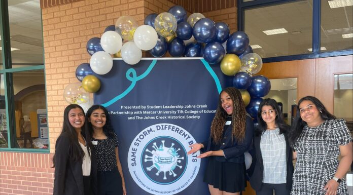Education professor leads project creating living history exhibit on COVID-19 Five female students stand in front of a large poster with balloons.